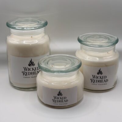 “Wicked Redhead luxury glass jar candles with white wax and clear glass lids displayed on a white background.